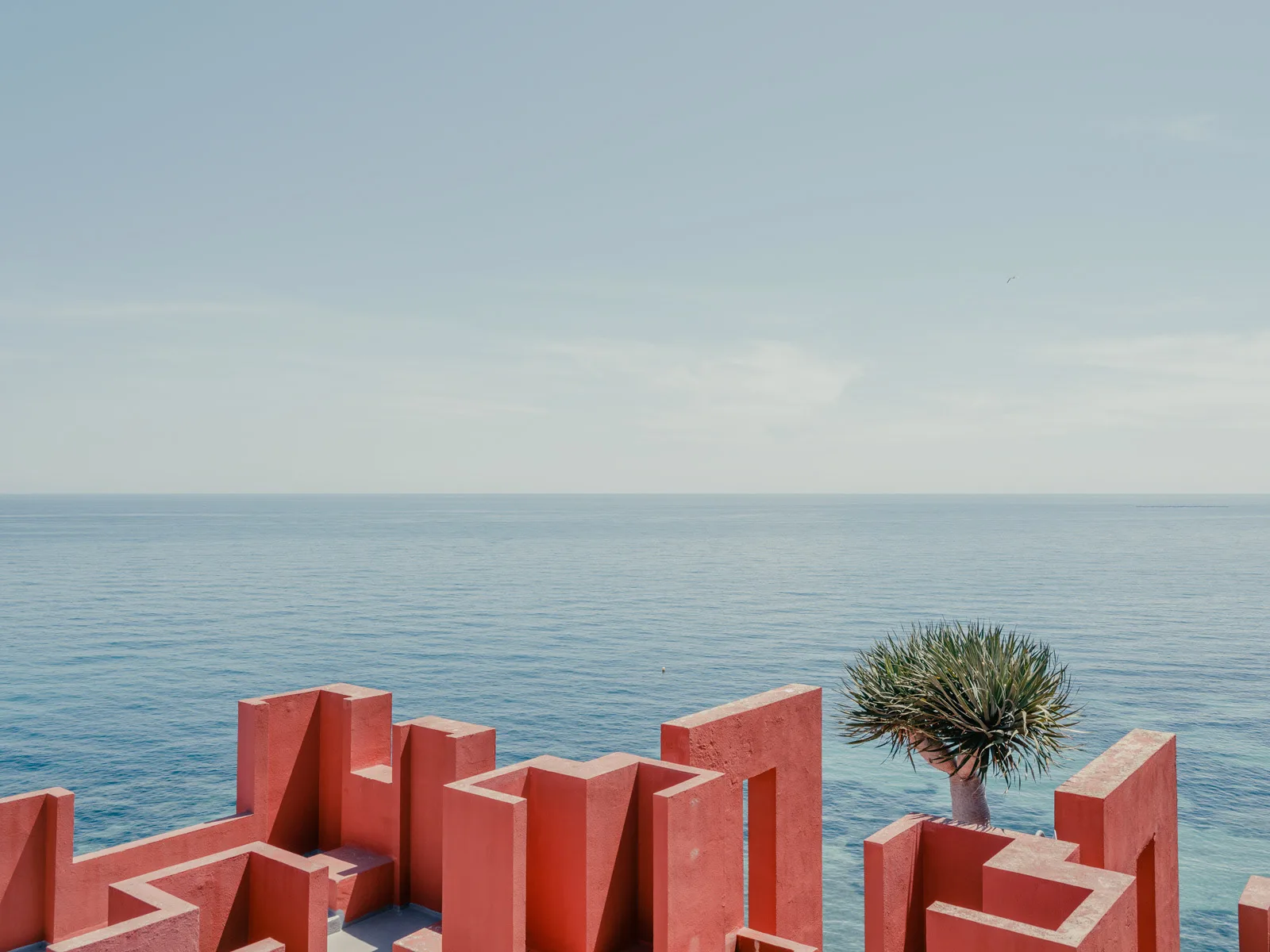 A red, geometric structure overlooks a calm blue sea — limited edition fine art print by Ludwig Favre A red, geometric structure overlooks a calm blue sea — limited edition fine art print by Ludwig Favre