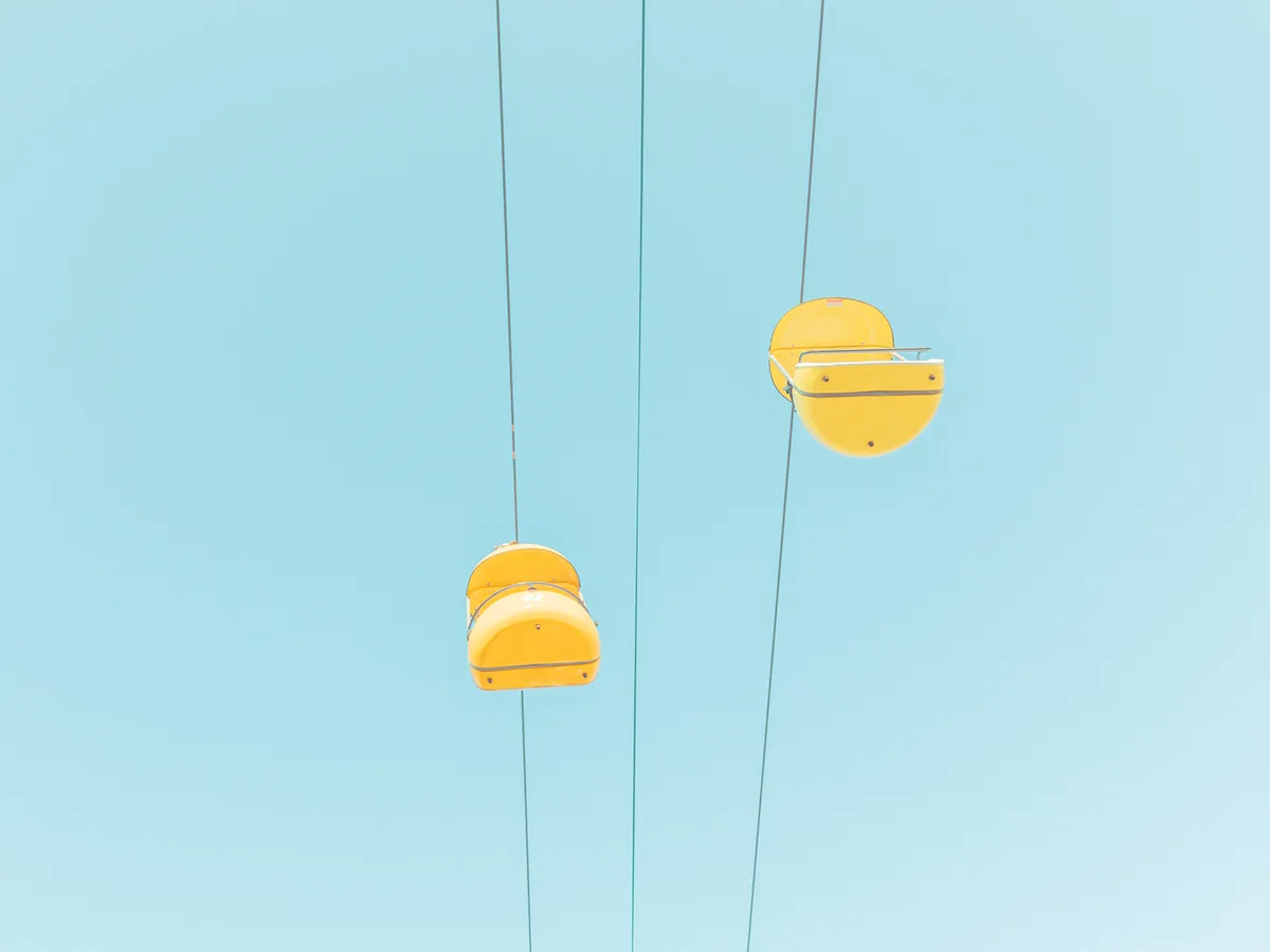 Two yellow ski gondola chairs suspended against a clear sky — limited edition fine art print by Ludwig Favre Two yellow ski gondola chairs suspended against a clear sky — limited edition fine art print by Ludwig Favre