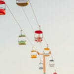 Colorful gondola cars suspended above Santa Cruz amusement park — limited edition fine art print by Ludwig Favre