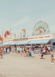 A lively Coney Island beach scene with the Cyclone roller coaster — limited edition fine art print by Ludwig Favre