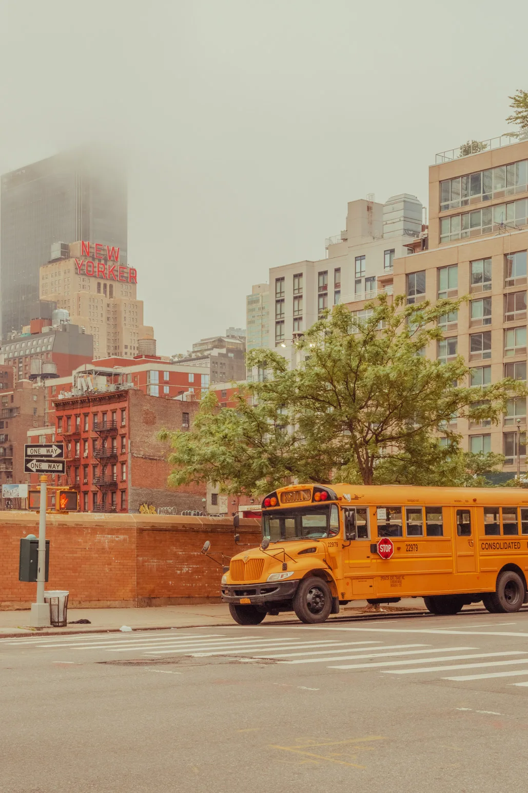 Yellow school bus on a New York street with brick buildings — limited edition fine art print by Ludwig Favre