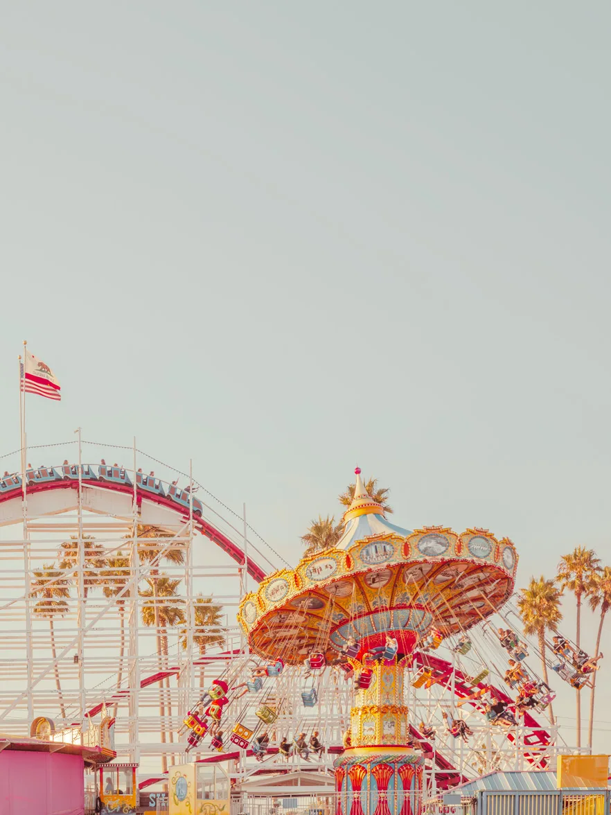 Vintage carousel in Santa Cruz with palm trees and the Pacific Ocean visible — limited edition fine art print by Ludwig Favre