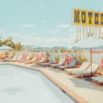 Retro motel pool scene on the California coast with turquoise umbrellas — limited edition fine art print by Ludwig Favre