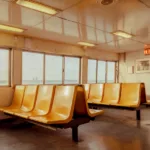 Empty orange seats and a distant skyline on the Staten Island ferry — limited edition fine art print by Ludwig Favre