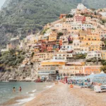 Colorful Positano coastline with tiered houses, sandy beach — limited edition fine art print by Ludwig Favre