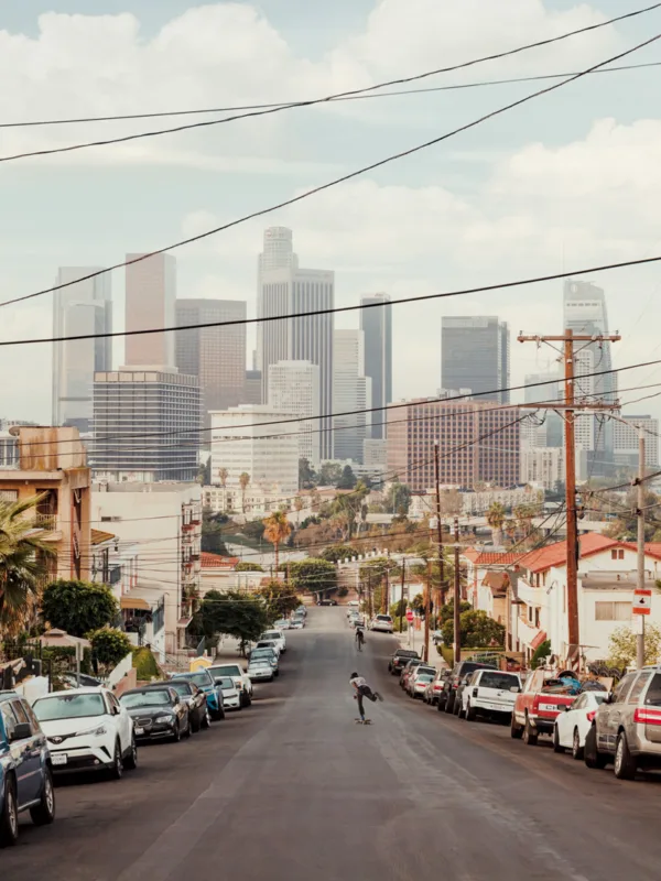 A skateboarder rides down a street with the Los Angeles skyline in warm light — limited edition fine art print by Ludwig Favre A skateboarder rides down a street with the Los Angeles skyline in warm light — limited edition fine art print by Ludwig Favre