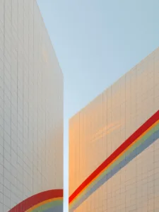Two white tiled towers in Berlin crossed by a painted rainbow under a pale blue sky — limited edition fine art print by Ludwig Favre