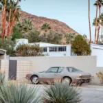 Vintage car parked on a midcentury driveway in Palm Springs, California, with desert landscaping and the San Jacinto mountains, limited edition fine art print by Ludwig Favre