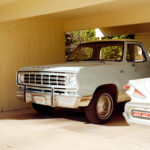 A mint-condition classic car, possibly a 1970s Dodge pickup, in an underground garage illuminated by warm afternoon light, limited edition fine art print by Ludwig Favre