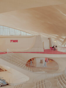 TWA Flight Center interior at JFK, New York: curved concrete, red carpet and TWA sign — limited edition fine art print by Ludwig Favre