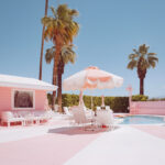 Pink motel pool deck with a striped umbrella and palm trees, Palm Springs, limited edition fine art photograph by Ludwig Favre