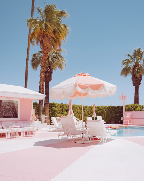 Pink motel pool deck with a striped umbrella and palm trees, Palm Springs, limited edition fine art photograph by Ludwig Favre