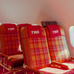 Red plaid TWA airline seats beside a cabin window, limited edition fine art photograph by Ludwig Favre