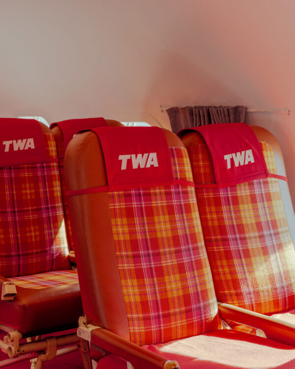 Red plaid TWA airline seats beside a cabin window, limited edition fine art photograph by Ludwig Favre