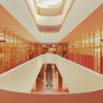 Symmetrical view of an orange and cream staircase under a bright oval skylight in San Francisco, fine art print by Ludwig Favre