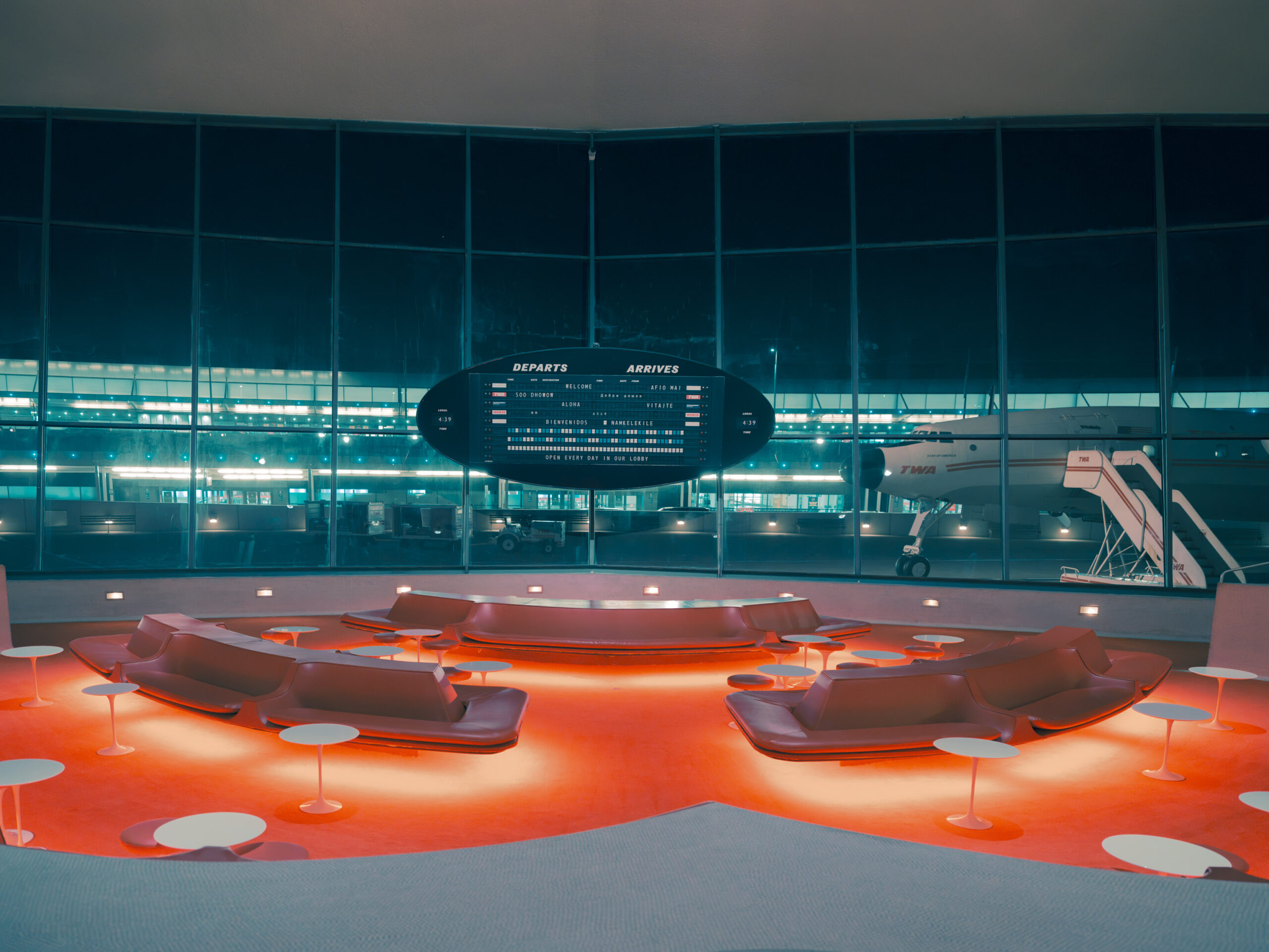 Red curved lounge seating and flight board at TWA Hotel New York print, limited edition fine art print by Ludwig Favre